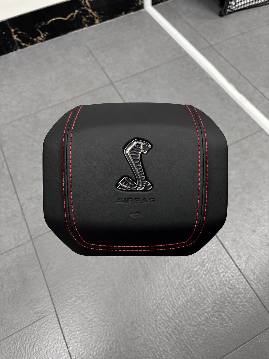 Black custom airbag cover with Cobra emblem and red stitching