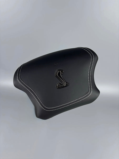 Black custom airbag cover with Cobra emblem and white stitching